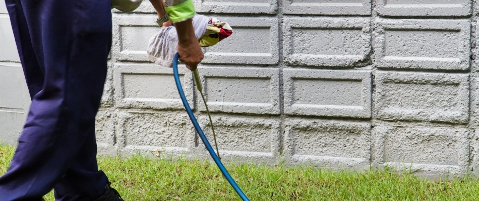 Professional spraying up base walls of home with pest control treatment in Chandler, AZ.